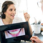 Kieferorthopäde zeigt Patienten Probe eines Zahnimplantats