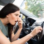 Frau, die sich ihre Nase wegen schlechten Geruchs im Auto, zuhält