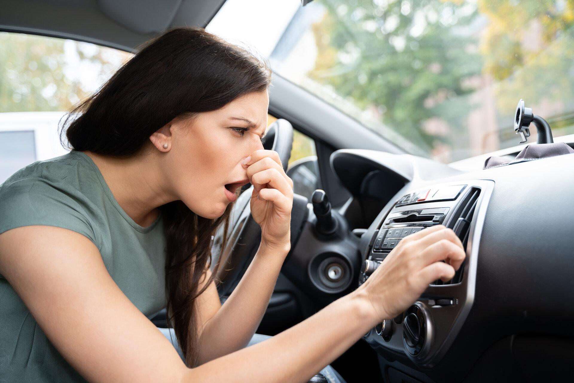 Frau, die sich ihre Nase wegen schlechten Geruchs im Auto, zuhält