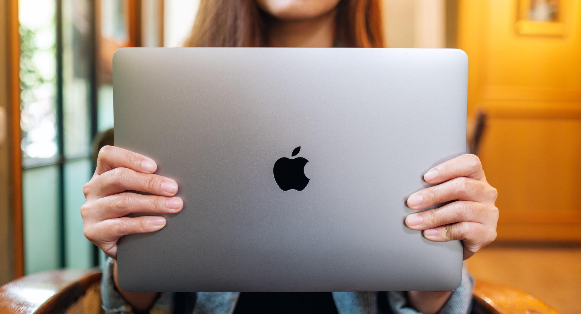 Eine Frau, die einen Apple MacBook Pro Laptop in den Händen hochält